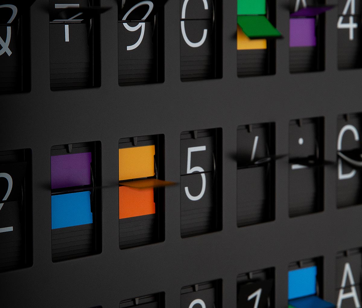 Vestaboard Bits mid-flip showing letters, numbers, and colours