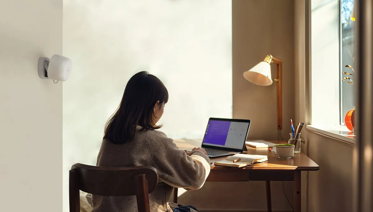Aqara Presence Sensor FP1E on the wall beside a person working at a desk