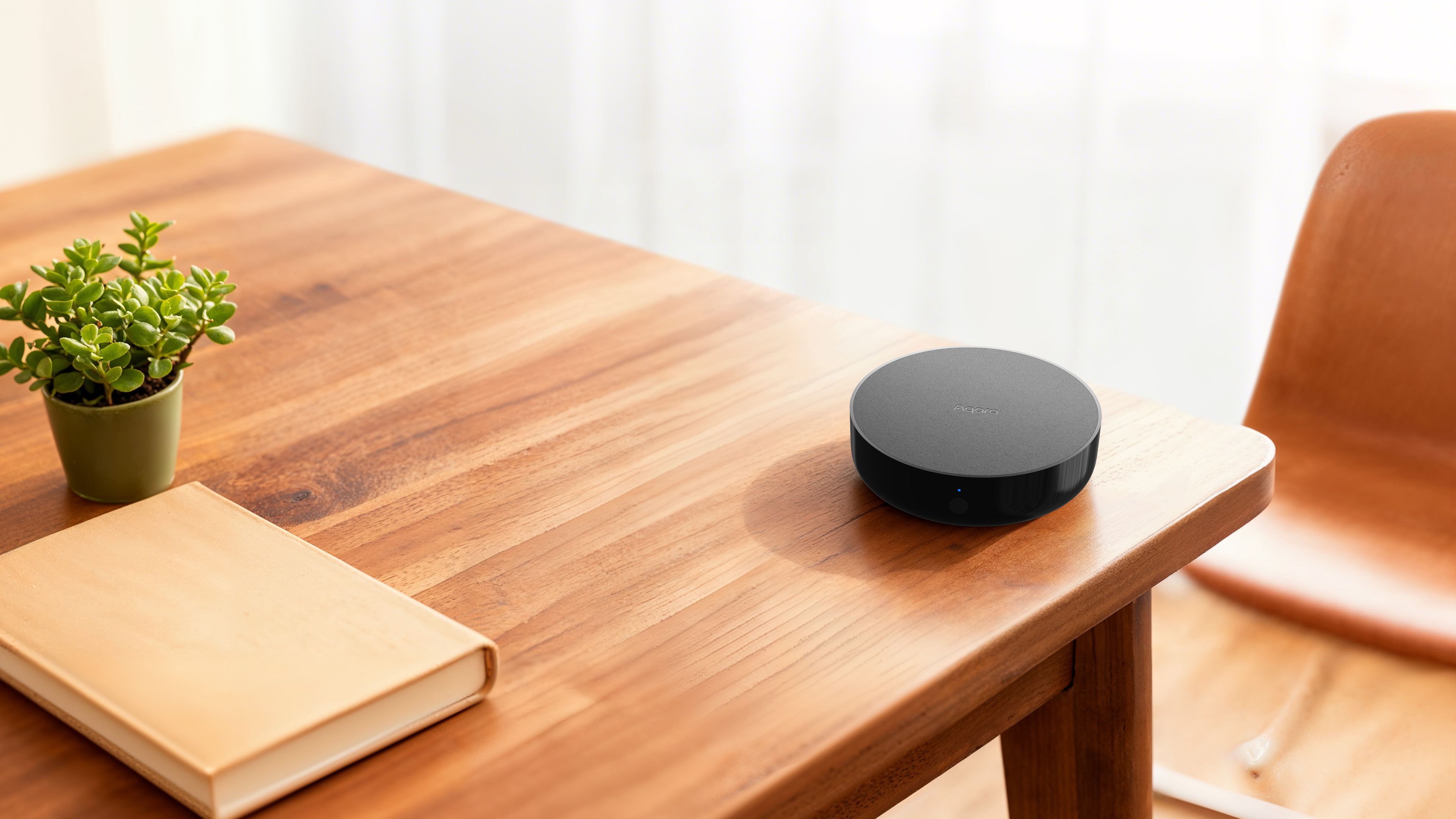 Aqara Hub M200 sitting on a wooden desk in a sunlit living room