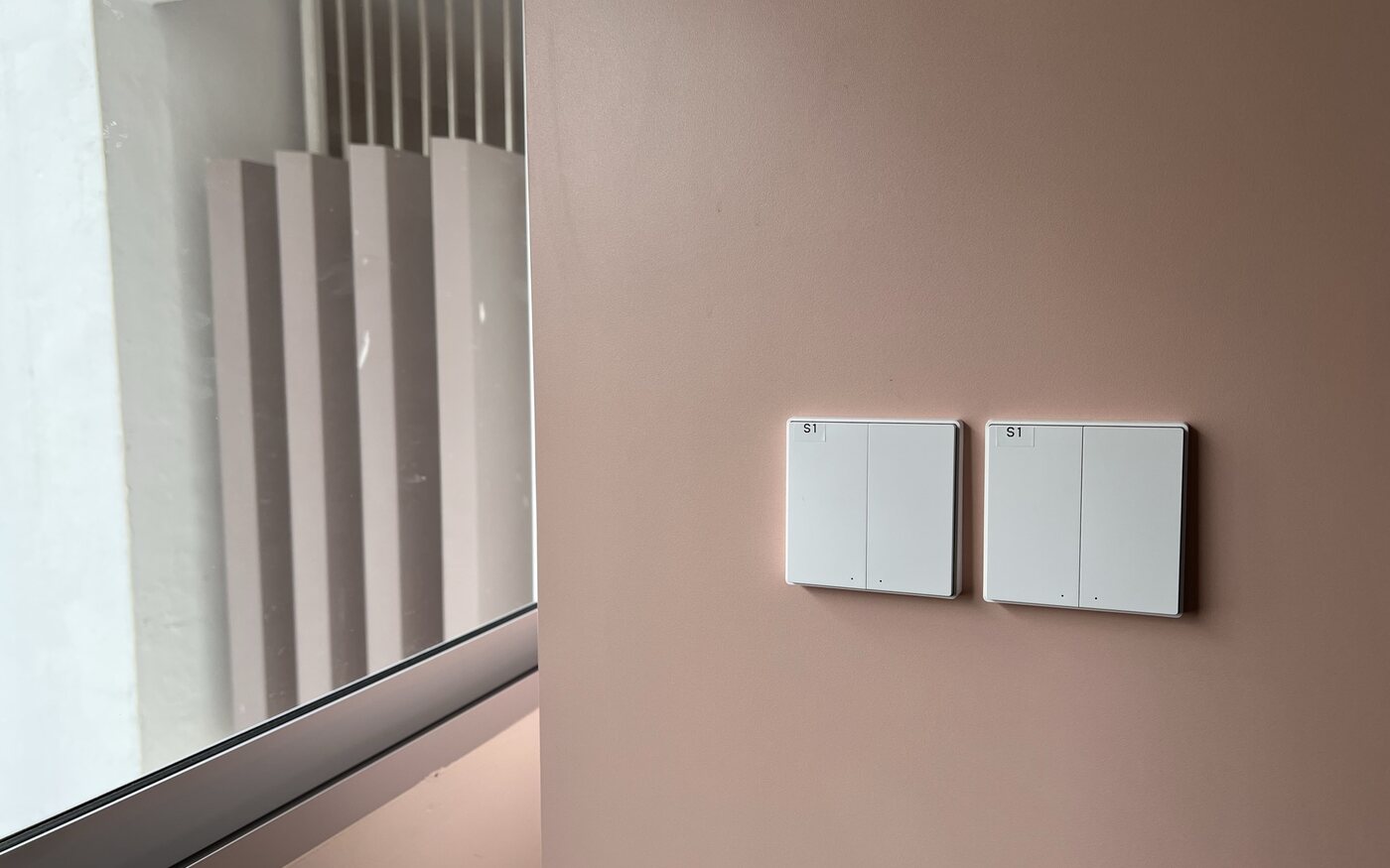 Two Aqara smart wall switches installed beside a window