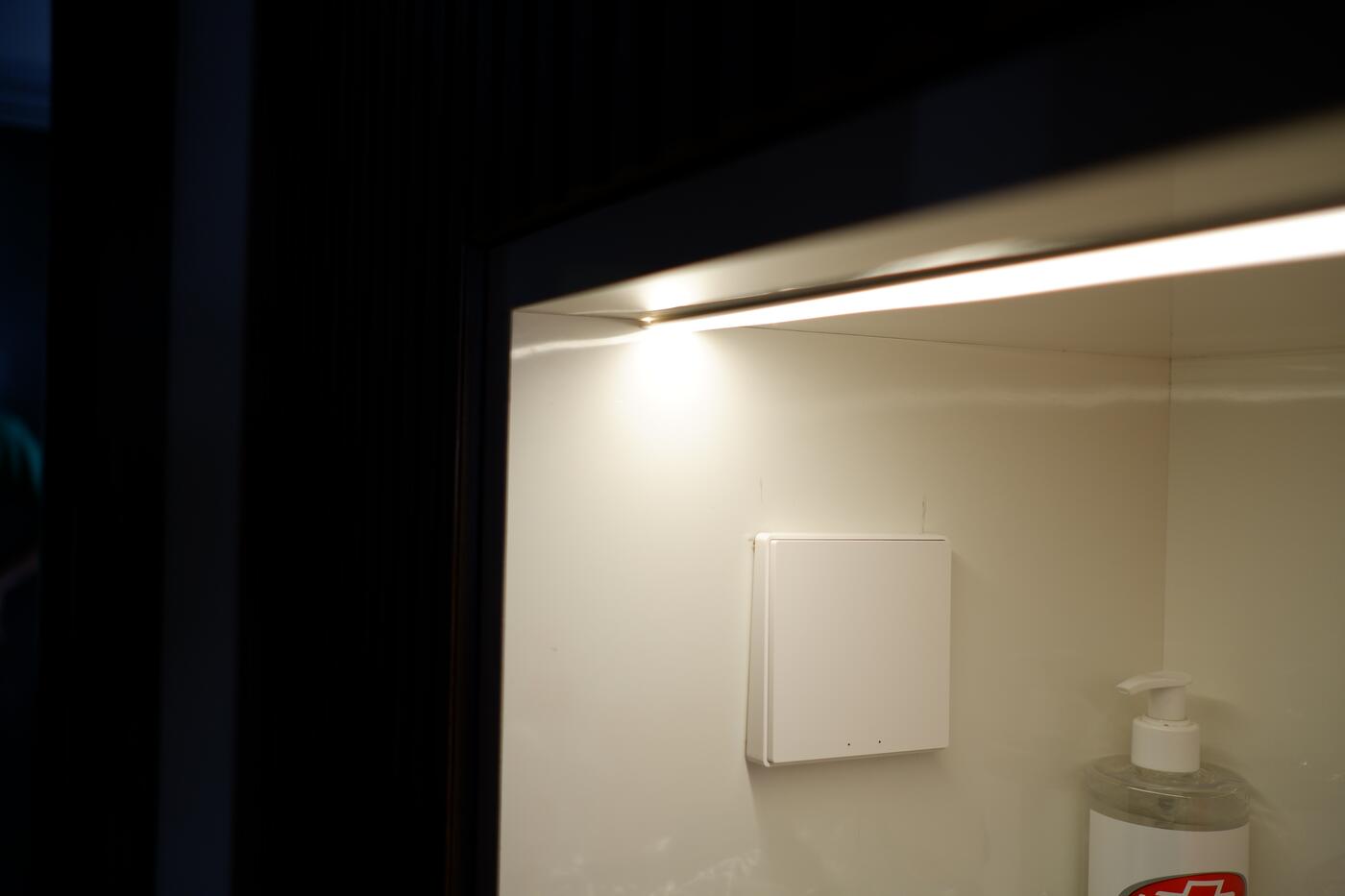 Aqara wireless light switch installed beside a bathroom mirror