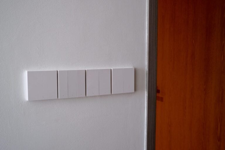 Four white wall switch panels in a horizontal row beside a timber door.