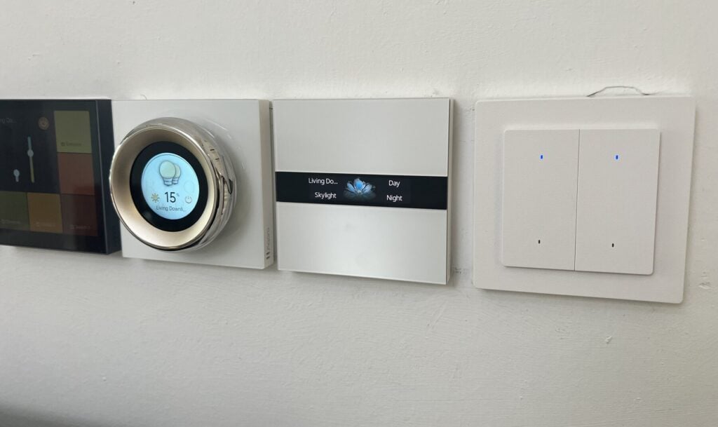 A touchscreen, a dial, a scene panel and a wall switch side by side